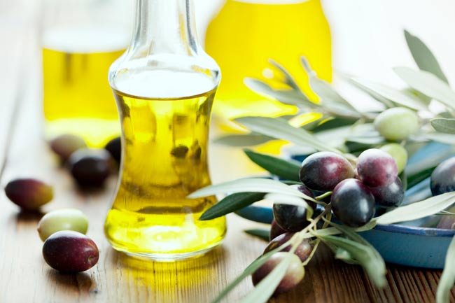 An olive-oil bottle and olivee-tree branch on the table
